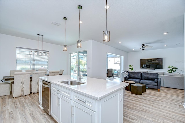 kitchen featuring a sink, a ceiling fan, light wood-style floors, white cabinets, and decorative light fixtures