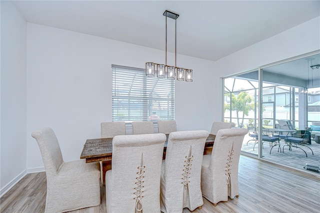 dining space with light wood-style flooring, a chandelier, and baseboards
