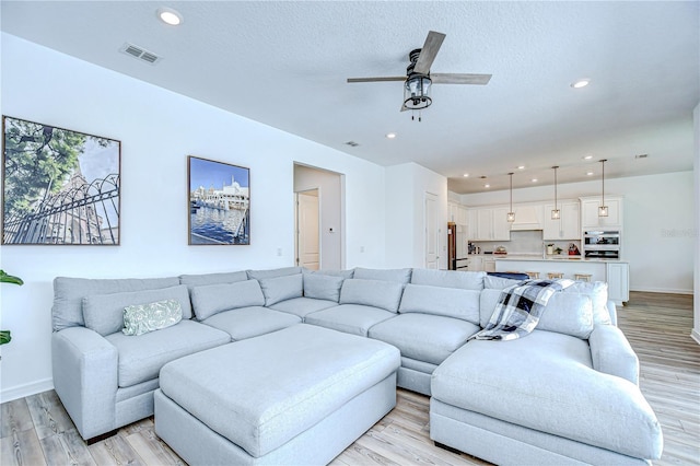 living area featuring a ceiling fan, light wood-style floors, baseboards, and recessed lighting