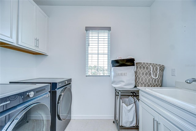 washroom featuring cabinet space, washing machine and clothes dryer, and baseboards