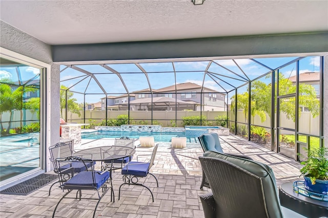 view of patio with glass enclosure and a pool with connected hot tub