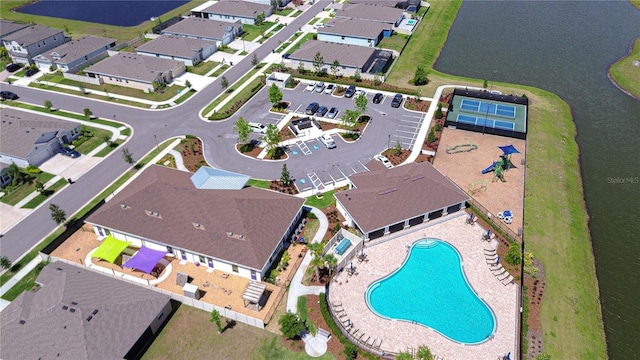 aerial view of property and surrounding area featuring a pool area, a large body of water, and nearby suburban area