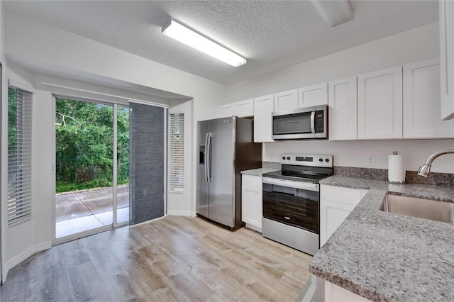 15855 Fishhawk View Dr, Lithia, FL 33547 - kitchen with appliances with stainless steel finishes, a sink, white cabinetry, light wood finished floors, and a textured ceiling