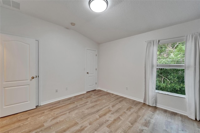 15855 Fishhawk View Dr, Lithia, FL 33547 - unfurnished room featuring lofted ceiling, light wood-type flooring, baseboards, and a textured ceiling