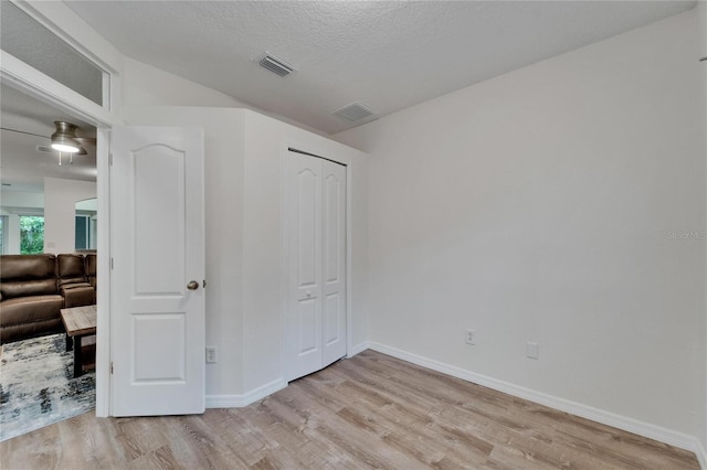 15855 Fishhawk View Dr, Lithia, FL 33547 - unfurnished bedroom featuring light wood-style floors, baseboards, a closet, and a textured ceiling