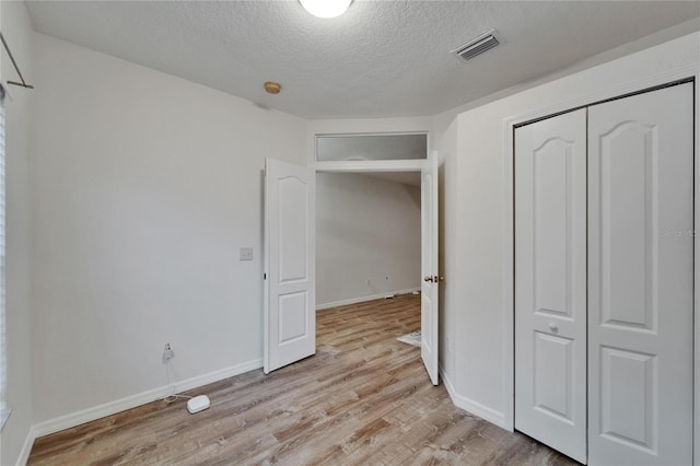 15855 Fishhawk View Dr, Lithia, FL 33547 - unfurnished bedroom featuring a textured ceiling, light wood-type flooring, a closet, and baseboards