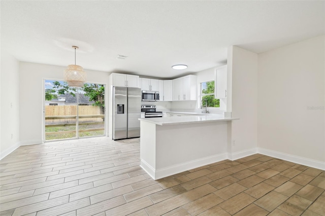 1801 E Navajo Ave, Tampa, FL 33612 - kitchen featuring appliances with stainless steel finishes, a peninsula, light countertops, white cabinets, and light wood-style floors