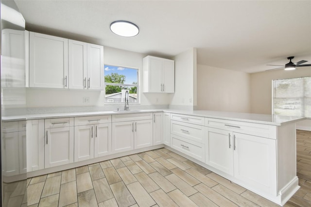 1801 E Navajo Ave, Tampa, FL 33612 - kitchen featuring a sink, a peninsula, light countertops, and white cabinetry