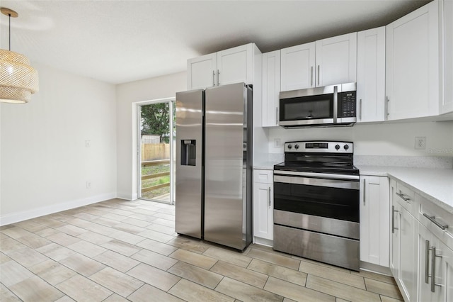 1801 E Navajo Ave, Tampa, FL 33612 - kitchen with stainless steel appliances, light countertops, white cabinetry, and decorative light fixtures