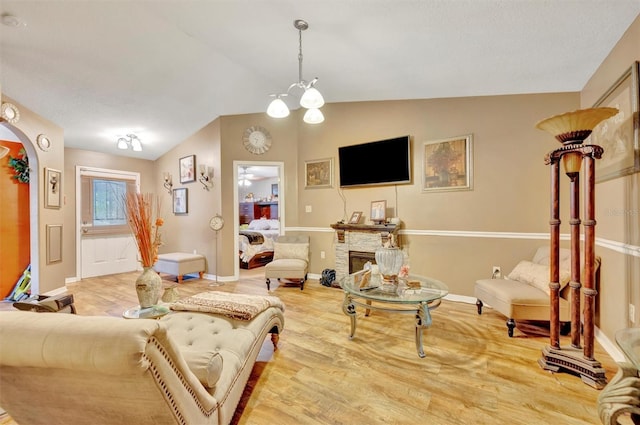 1505 E 99th Ave, Tampa, FL 33612 - living room featuring vaulted ceiling, arched walkways, baseboards, light wood finished floors, and a fireplace