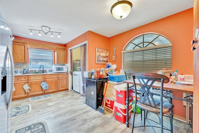 1505 E 99th Ave, Tampa, FL 33612 - kitchen with white microwave, light wood-type flooring, washer / clothes dryer, stainless steel fridge, and a sink