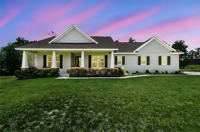 ranch-style home featuring covered porch, a front yard, and stucco siding