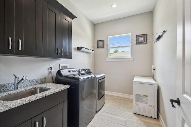 laundry area featuring independent washer and dryer, cabinet space, baseboards, and light wood-style flooring