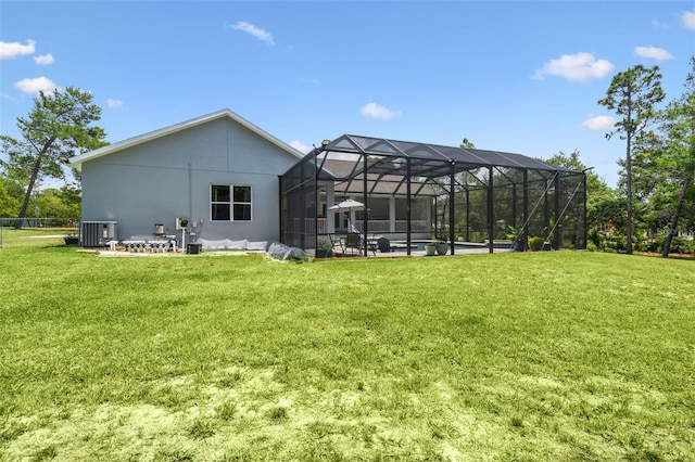 back of property featuring central AC, a yard, glass enclosure, stucco siding, and a patio