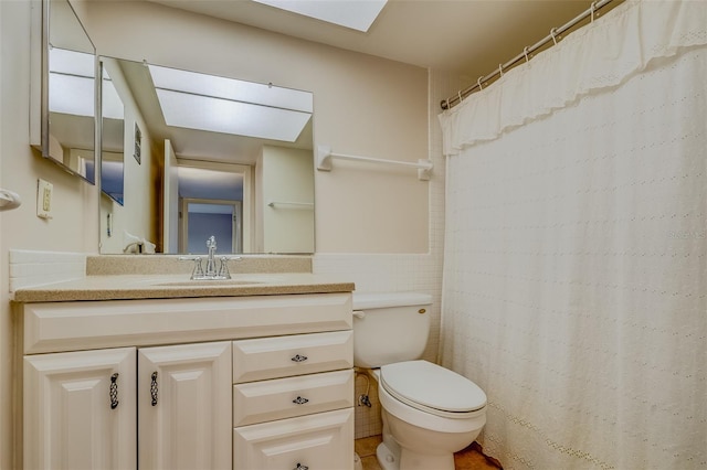 1221 Drew St Unit E12, Clearwater, FL 33755 - bathroom with toilet, vanity, a skylight, and tile walls