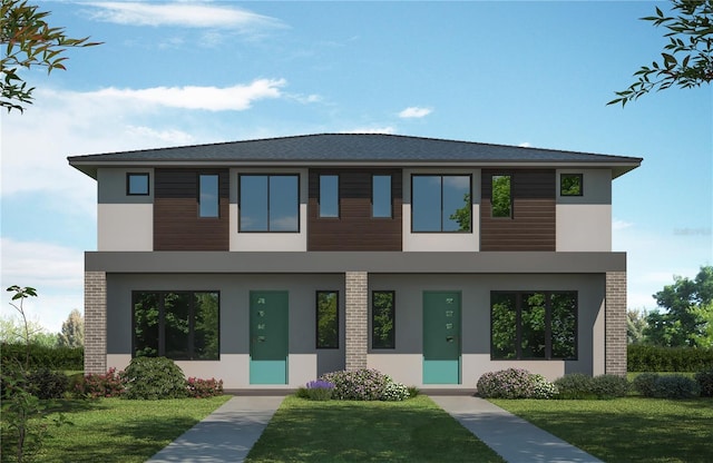 modern home with stucco siding, a front lawn, and brick siding