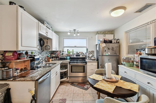 361 Colonial Ct, Dunedin, FL 34698 - kitchen featuring stainless steel appliances, a sink, decorative backsplash, light tile patterned floors, and dark stone counters