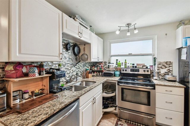 361 Colonial Ct, Dunedin, FL 34698 - kitchen with stainless steel appliances, decorative backsplash, white cabinetry, a sink, and light stone counters