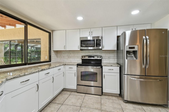 854 Village Way, Palm Harbor, FL 34683 - kitchen with appliances with stainless steel finishes, white cabinetry, light tile patterned floors, a textured ceiling, and recessed lighting