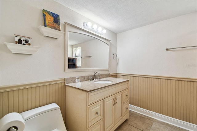 854 Village Way, Palm Harbor, FL 34683 - half bath with a wainscoted wall, vanity, a textured ceiling, tile patterned floors, and toilet