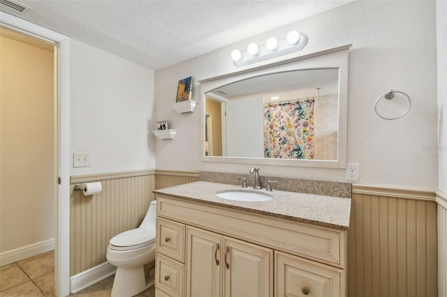 854 Village Way, Palm Harbor, FL 34683 - bathroom with wainscoting, toilet, a textured ceiling, vanity, and tile patterned flooring