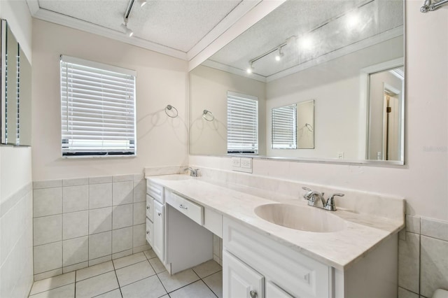 854 Village Way, Palm Harbor, FL 34683 - bathroom featuring rail lighting, tile patterned flooring, tile walls, double vanity, and a textured ceiling