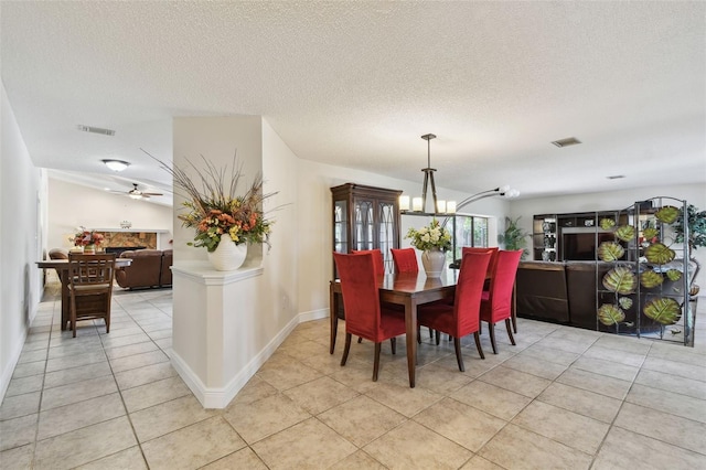 854 Village Way, Palm Harbor, FL 34683 - dining space featuring light tile patterned flooring, a chandelier, a textured ceiling, baseboards, and ceiling fan