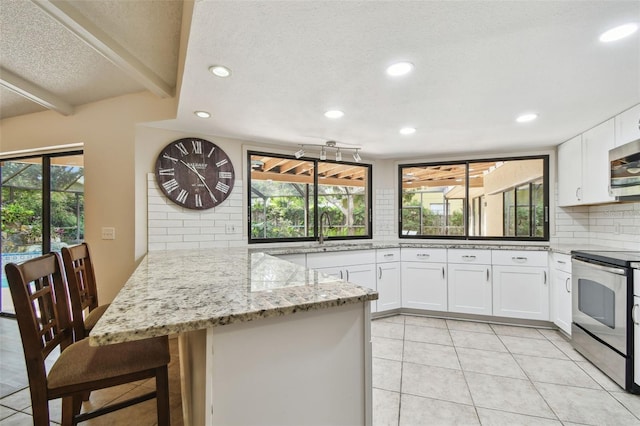 854 Village Way, Palm Harbor, FL 34683 - kitchen with appliances with stainless steel finishes, recessed lighting, tasteful backsplash, a peninsula, and white cabinets