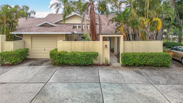 120 Colony S Dr, Tarpon Springs, FL 34689 - view of front facade with stucco siding, a fenced front yard, a shingled roof, driveway, and an attached garage