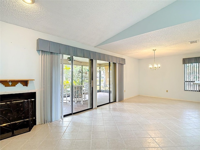 120 Colony S Dr, Tarpon Springs, FL 34689 - spare room with a textured ceiling, light tile patterned flooring, a chandelier, and a glass covered fireplace