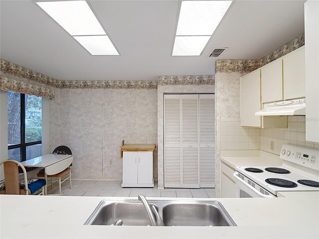 120 Colony S Dr, Tarpon Springs, FL 34689 - kitchen with white range with electric cooktop, under cabinet range hood, a sink, light countertops, and tasteful backsplash