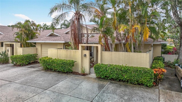 120 Colony S Dr, Tarpon Springs, FL 34689 - view of front of property with stucco siding, a fenced front yard, an attached garage, and a gate