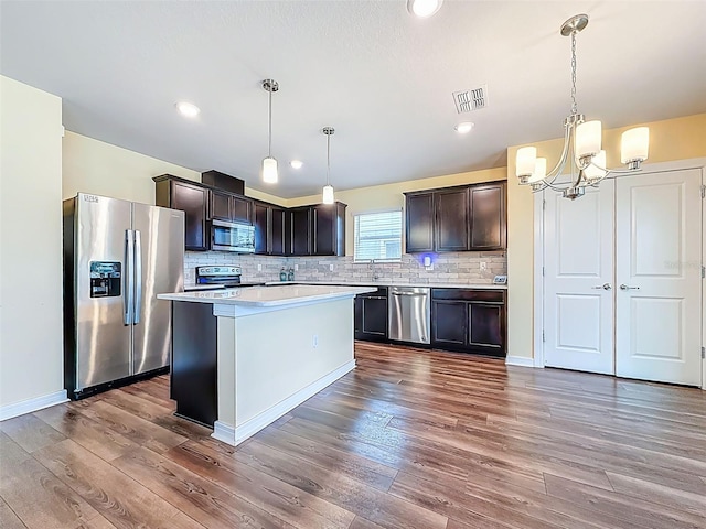 9324 Rally Spring Loop, Wesley Chapel, FL 33545 - kitchen with stainless steel appliances, light countertops, a chandelier, decorative backsplash, and dark wood finished floors