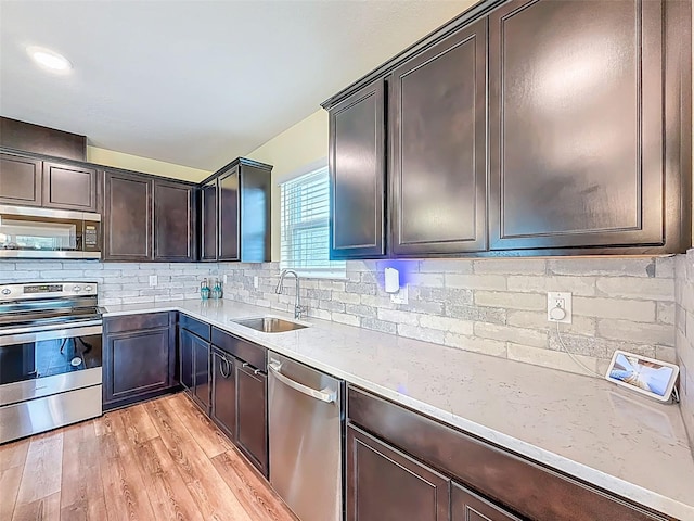 9324 Rally Spring Loop, Wesley Chapel, FL 33545 - kitchen with stainless steel appliances, a sink, light wood-type flooring, tasteful backsplash, and dark brown cabinetry