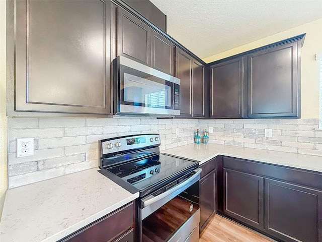 9324 Rally Spring Loop, Wesley Chapel, FL 33545 - kitchen with stainless steel appliances, tasteful backsplash, dark brown cabinetry, light wood-type flooring, and light stone countertops