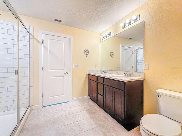 9324 Rally Spring Loop, Wesley Chapel, FL 33545 - bathroom featuring toilet, a shower stall, double vanity, a textured ceiling, and baseboards
