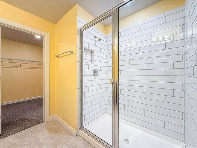9324 Rally Spring Loop, Wesley Chapel, FL 33545 - bathroom featuring a shower stall, a walk in closet, and baseboards