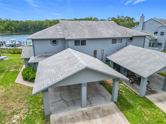 11122 W Cove Harbor Dr Unit 112, Crystal River, FL 34428 - rear view of house featuring a yard, stucco siding, a water view, a shingled roof, and a carport
