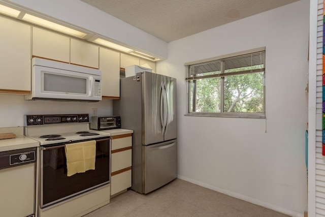 1241 S Martin Luther King Jr Ave Unit 302, Clearwater, FL 33756 - kitchen with white microwave, range with electric stovetop, freestanding refrigerator, light countertops, and cream cabinets