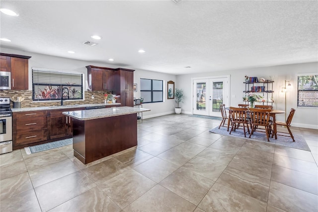 4821 S Gachet Blvd, Lakeland, FL 33813 - kitchen with appliances with stainless steel finishes, a sink, tasteful backsplash, french doors, and a center island