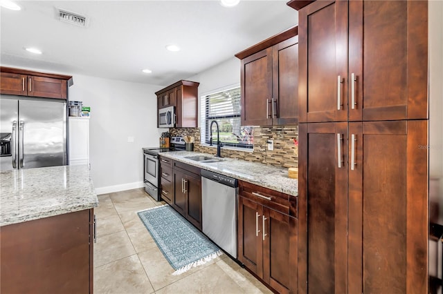 4821 S Gachet Blvd, Lakeland, FL 33813 - kitchen with stainless steel appliances, a sink, decorative backsplash, light stone countertops, and recessed lighting
