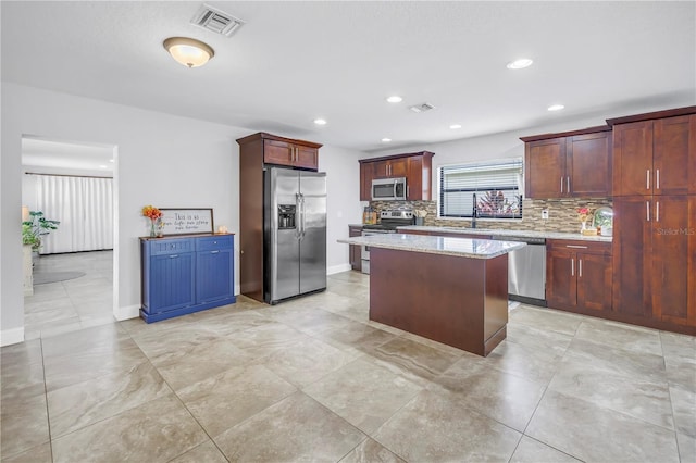 4821 S Gachet Blvd, Lakeland, FL 33813 - kitchen featuring stainless steel appliances, tasteful backsplash, a kitchen island, light stone counters, and recessed lighting
