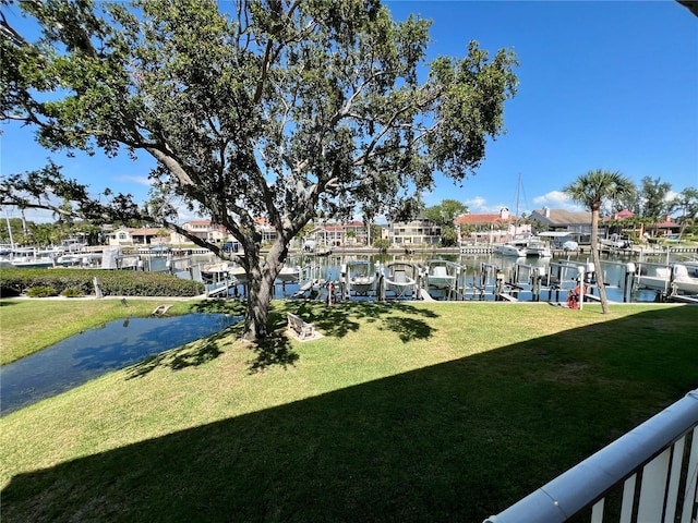 view of grassy yard with a water view, a boat dock, and boat lift