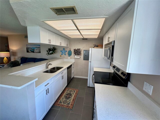 kitchen with a sink, appliances with stainless steel finishes, baseboards, a peninsula, and white cabinets