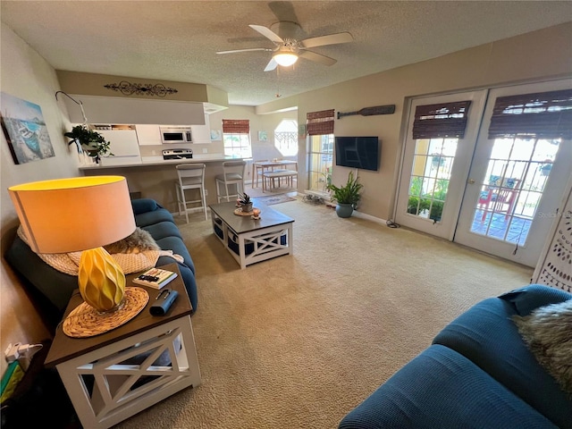 living room with ceiling fan, light colored carpet, a textured ceiling, and baseboards