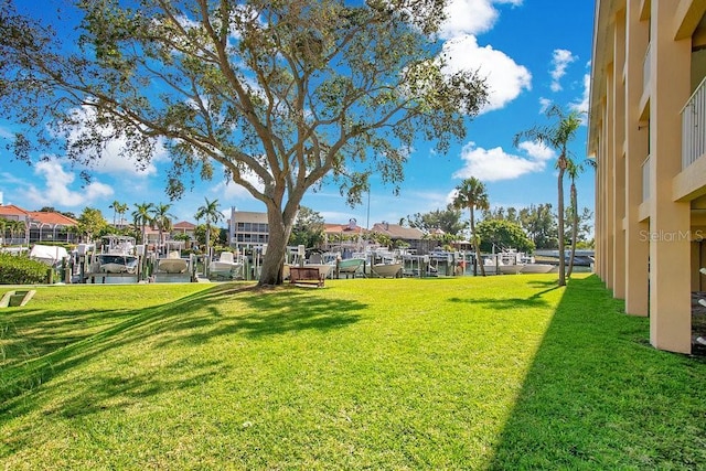 view of community with a boat dock, a lawn, and boat lift