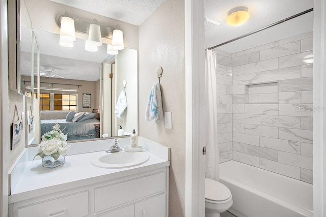 ensuite bathroom with a textured ceiling, toilet, ceiling fan, vanity, and shower / bath combo with shower curtain