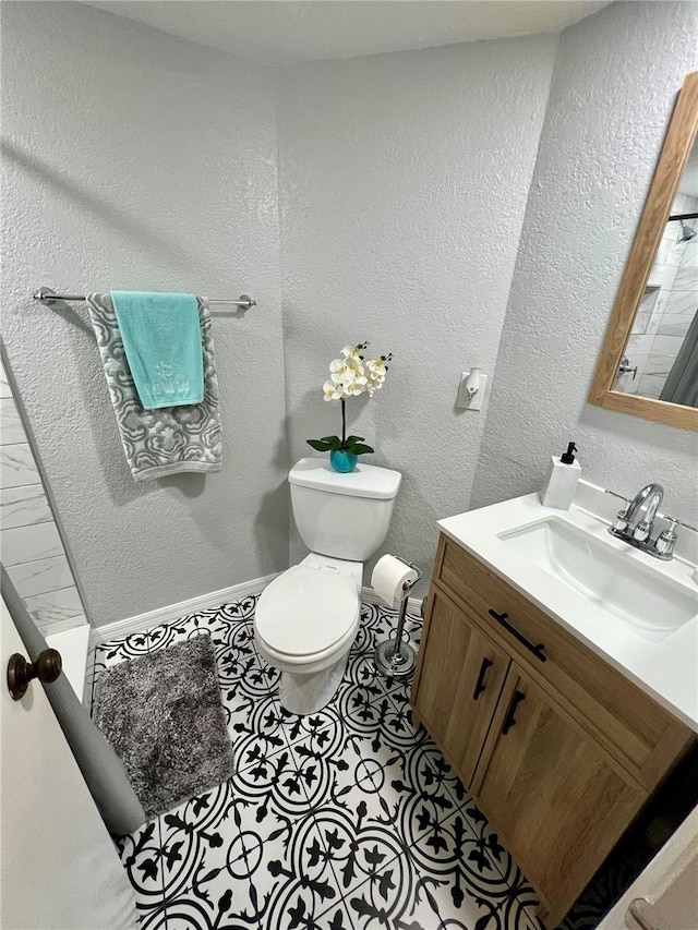 bathroom featuring toilet, a textured wall, vanity, and tile patterned flooring