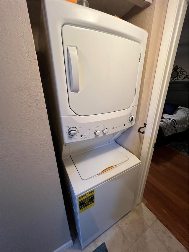 washroom featuring stacked washing machine and dryer and a textured wall