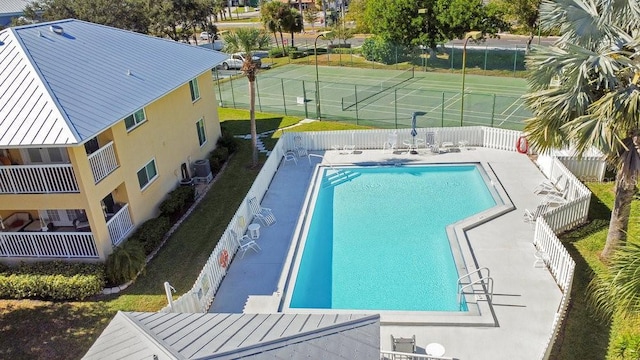 community pool featuring fence and a tennis court